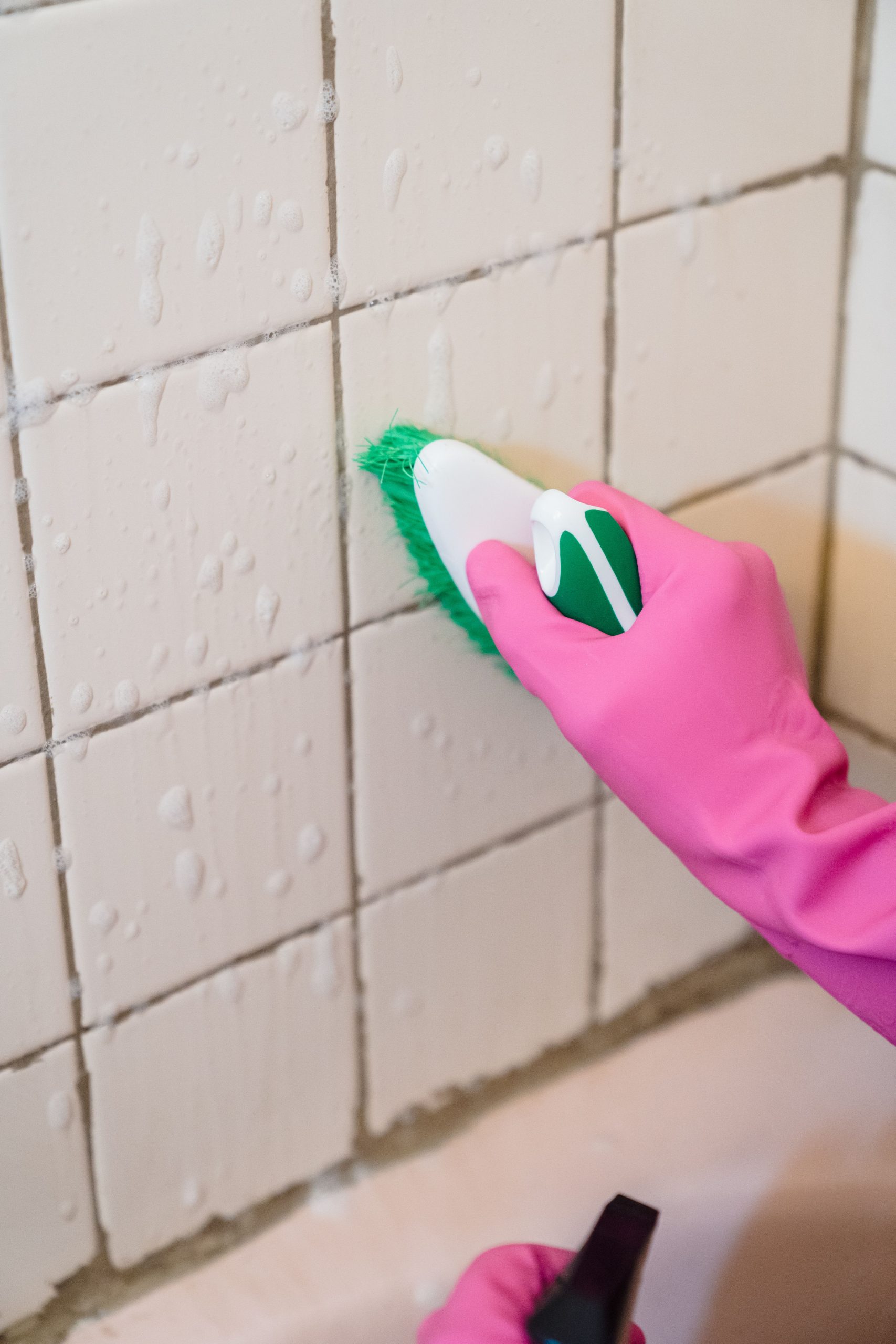 Cleaner meticulously scrubbing bathroom tiles during a deep cleaning session in a Reading home